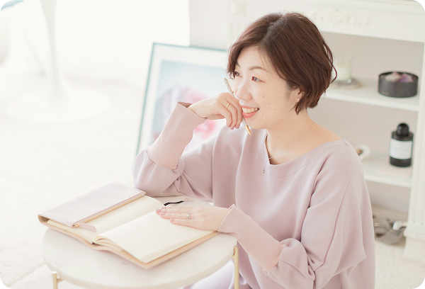 笑顔でノートを見る女性の写真